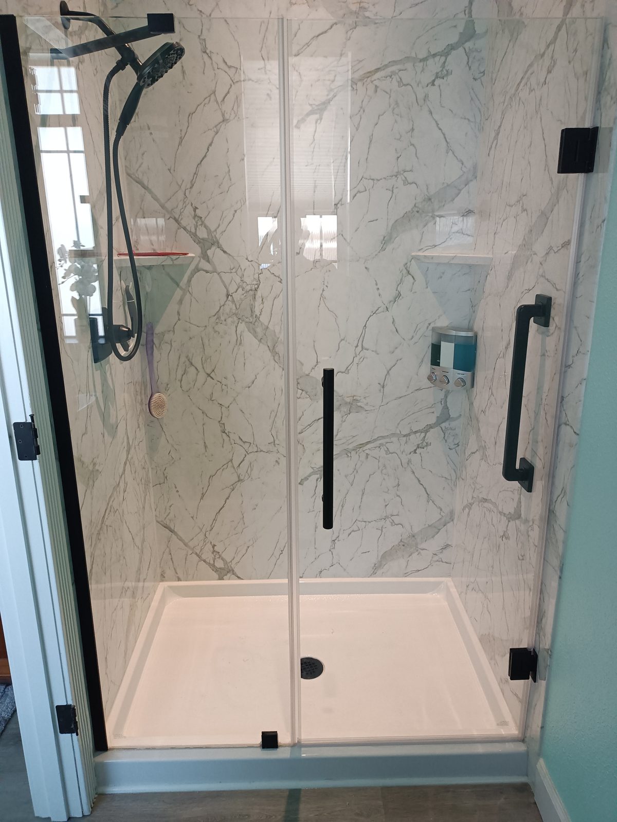 Calacatta-style shower with matte black fixtures and frameless glass door