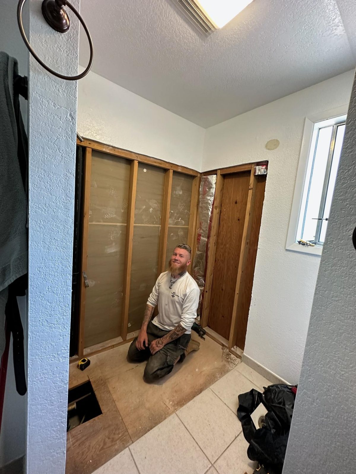 The owner of Thor Builders mid-demo on a bathroom remodel, smiling at the camera