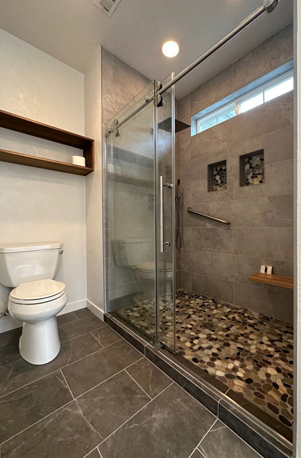 Finished walk-in tile shower with pebble floor and glass slider