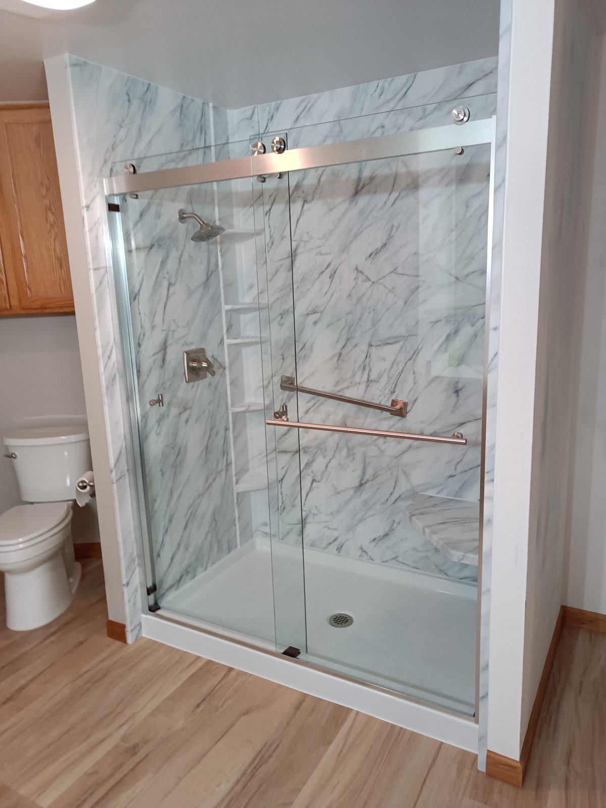 Walk-in shower with sliding glass door, marble-look surround and new LVP flooring